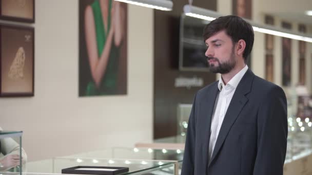 Young man in a suit with a beard buys a gift. — Stock Video