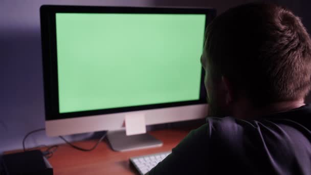 Человек за компьютером с зеленым экраном — стоковое видео