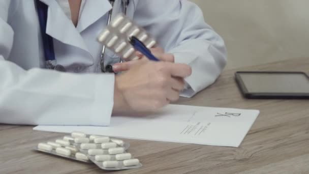 El médico mira las tabletas y escribe una receta . — Vídeo de stock