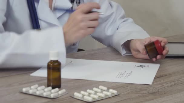 Az orvos néz ki a gyógyszert, és azt írja a recept. — Stock videók