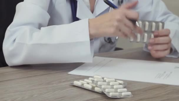El médico mira las tabletas y escribe una receta . — Vídeos de Stock
