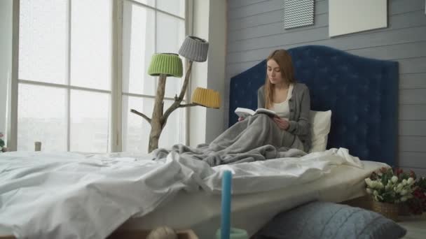 Blonde lezen van een boek tijdens de vergadering in bed. — Stockvideo