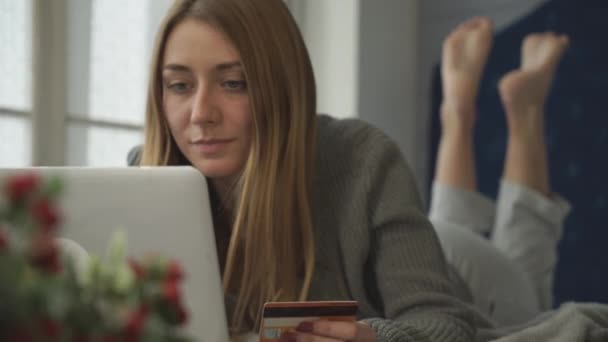 Biondo a letto con un computer portatile spende soldi . — Video Stock