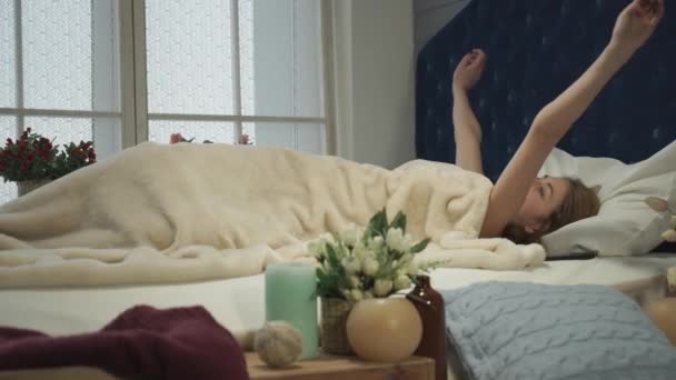 Blonde girl wakes up and stretches and picks up the phone — Stock Video