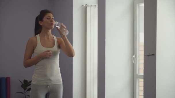Девушка пьет воду из бутылки в спортзале — стоковое видео