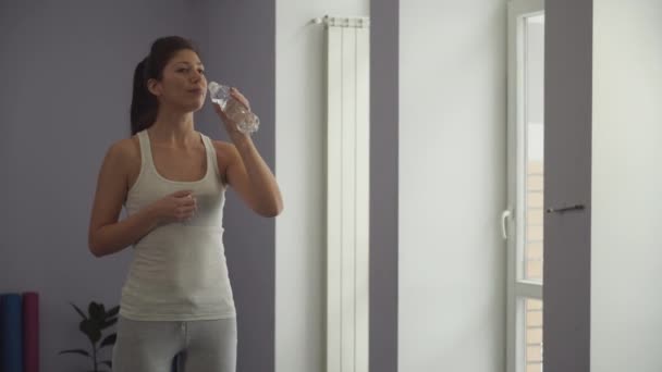 Girl drinks water from a bottle in a gym — Stock Video