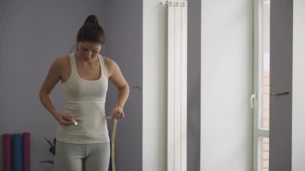 Mujer mide la cintura en el gimnasio . — Vídeo de stock