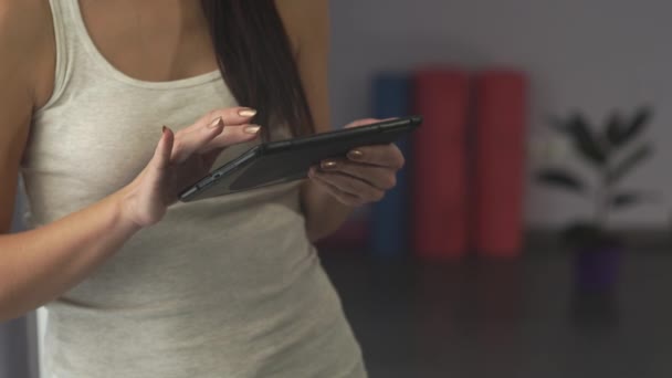 Chica con una tableta está en el gimnasio — Vídeo de stock