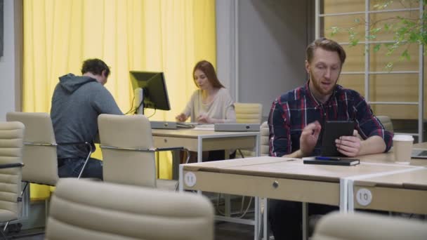 Un homme barbu parlant sur une tablette dans le bureau de l'éco — Video