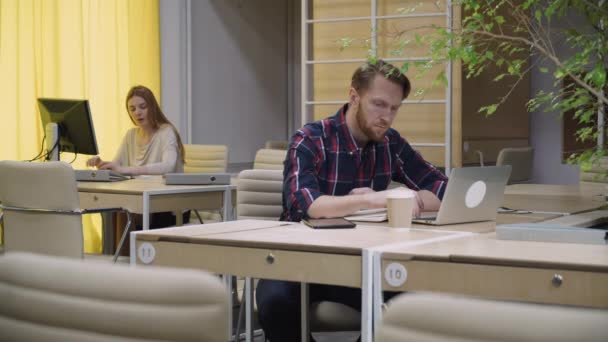 Homme travaillant dans l'ordinateur et prenant des notes sur un bloc-notes . — Video