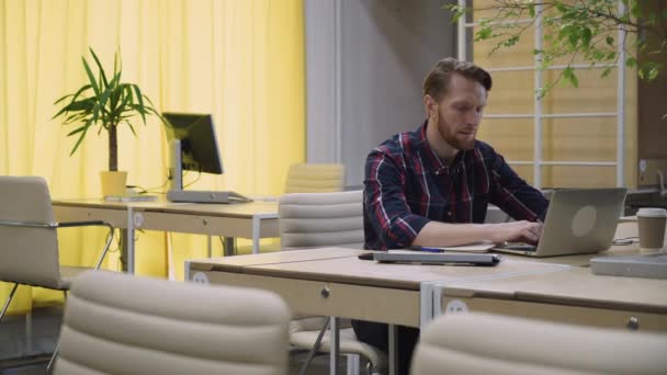 Bearded man with concentration works on the computer, looks up and smiles. — Stock Video