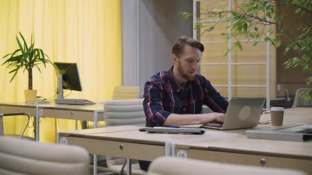 Bearded man with concentration works on the computer, looks up and smiles. — Stock Video