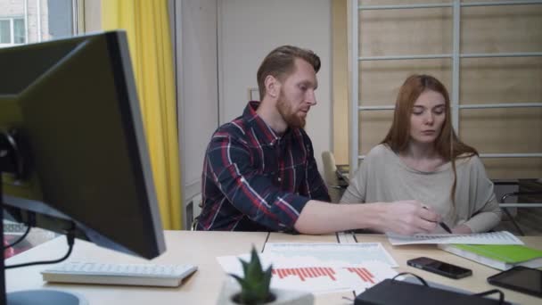 Bebaarde man toont nieuwe graphics vrouw. — Stockvideo