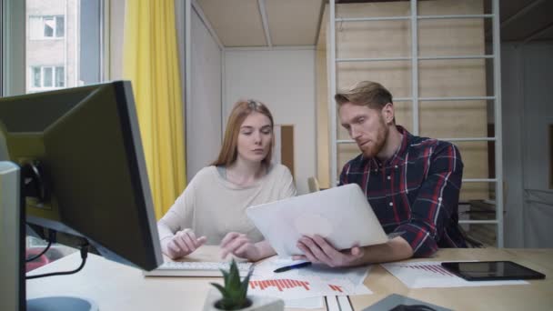 En skäggig man med en bärbar dator visar anställdas uppgifter att hon kommer in i datorn. — Stockvideo