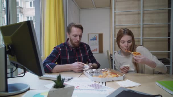 Робітники їдять піцу в офісі на робочому місці — стокове відео