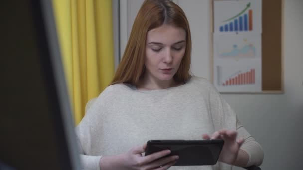 Roodharige meisje met een tablet surfen op Internet. — Stockvideo