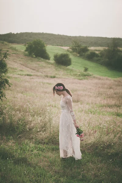 Jonge vrouw in witte kanten jurk lopen op weide — Stockfoto
