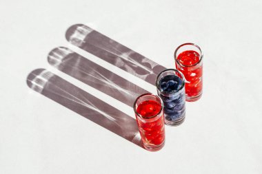 Üç kadehte yabanmersinli ve yabanmersinli su aşıları. Açık havada uzun ve güçlü gölgeler. 