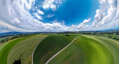 Orman ve tarladaki soyut panoramik hava manzarası. Muhteşem bulutlar ve küçük bir gezegen gibi uzayın eğriliği.                