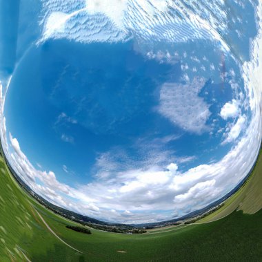 Orman ve tarladaki soyut panoramik hava manzarası. Muhteşem bulutlar ve küçük bir gezegen gibi uzayın eğriliği.                