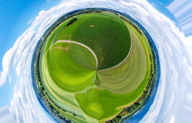 Orman ve tarladaki soyut panoramik hava manzarası. Muhteşem bulutlar ve küçük bir gezegen gibi uzayın eğriliği.                