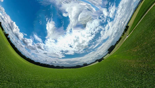 Orman ve tarladaki soyut panoramik hava manzarası. Muhteşem bulutlar ve küçük bir gezegen gibi uzayın eğriliği.                