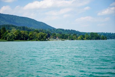 Bavyera Tegernsee Gölü 'nün manzarası ve arka planda dağlar olan kıyıları.                 