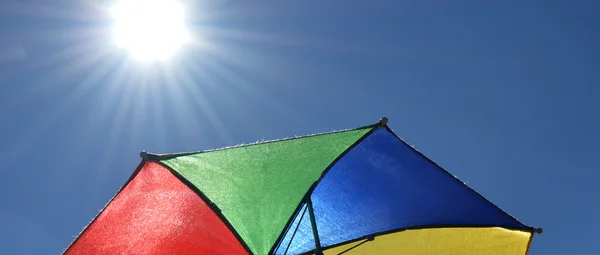 Soleil et parapluie sur fond bleu — Photo