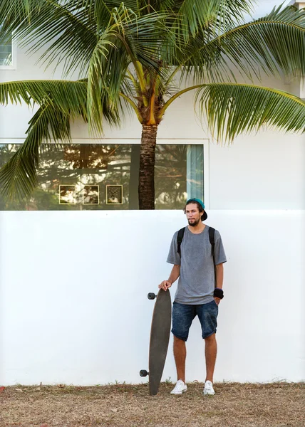 Ragazzo sullo skateboard al tramonto vicino al muro bianco — Foto Stock