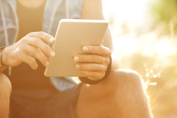 Tablet ensolarado nas mãos do cara na natureza — Fotografia de Stock