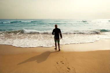 Sörfçü denizde sörf tahtası parlak renk ile duruyor.