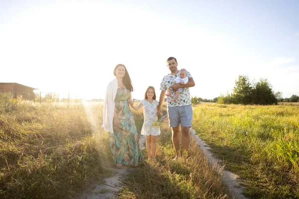 日落时分在田野里散步的一家人 — 图库照片