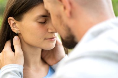 Birbirlerine aşık çiftler gün batımında sarılıp birbirlerine bakıyorlar.