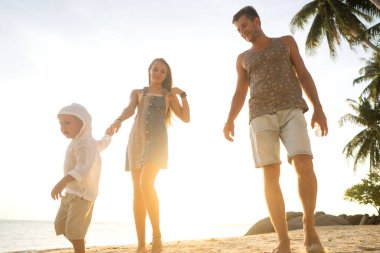 Mutlu aile gün batımında sahilde yürüyor.