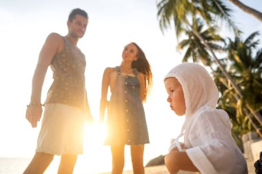 Mutlu aile gün batımında sahilde yürüyor.