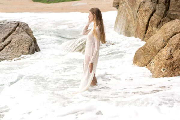 白いドレスを着た美しい女の子がビーチを歩いていて — ストック写真