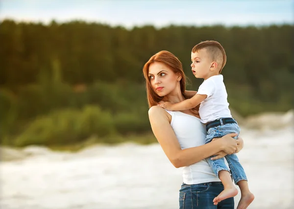 Felice madre e figlio sulla spiaggia tramonto — Foto Stock