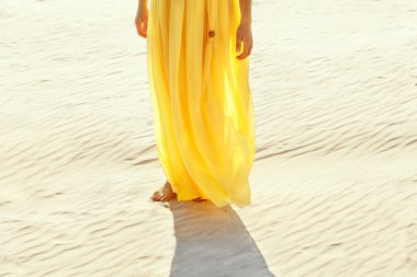 beyaz kum üzerinde yalınayak yürümek sarı elbiseli kız