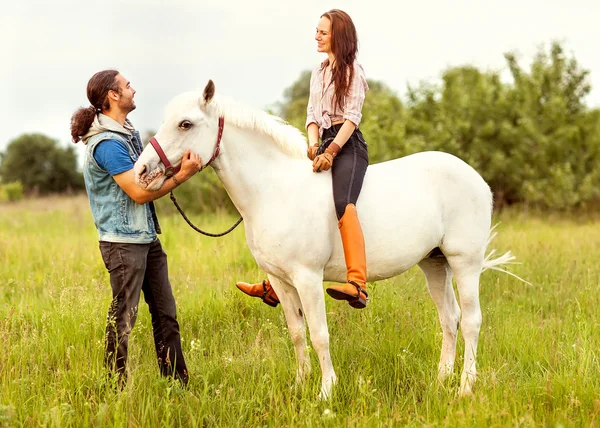 Giovane bella coppia con un cavallo al tramonto . — Foto Stock