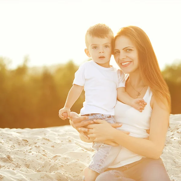 Happy mother and son on the beach sunset — Stock Photo, Image