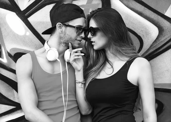 Fashion couple with sunglasses  near the wall graffiti — Stock Photo, Image