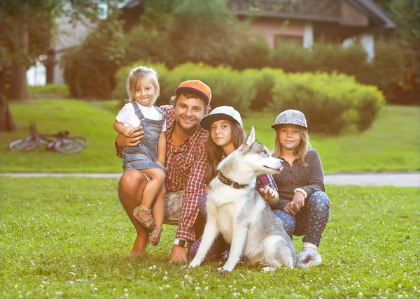 Pai e suas 3 filhas jazem na grama em óculos de sol felizes . — Fotografia de Stock