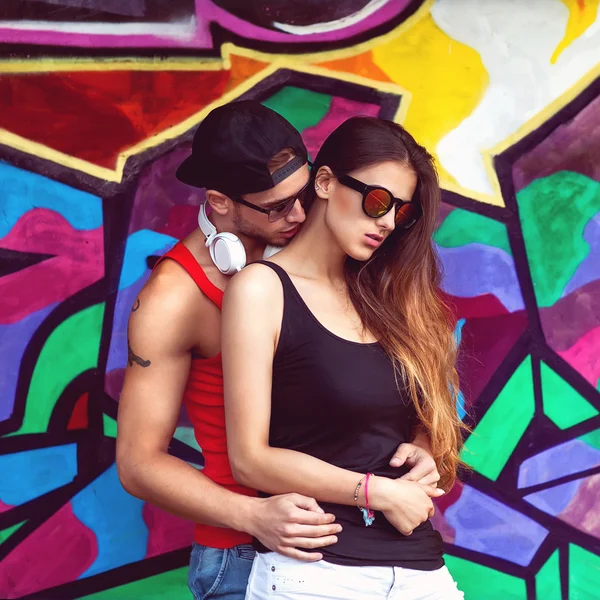 Casal de moda com óculos de sol perto da parede graffiti — Fotografia de Stock