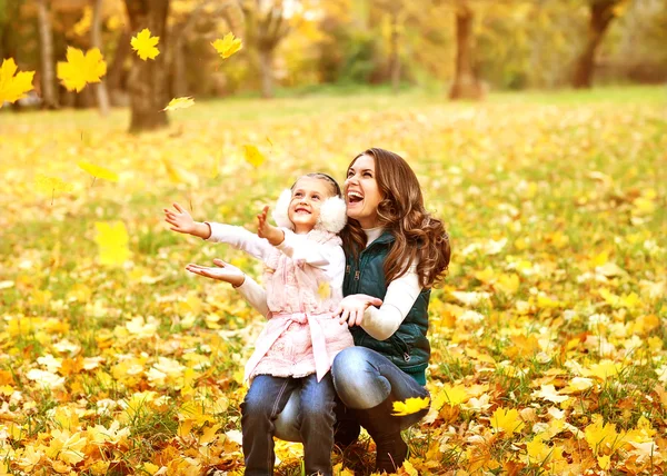 Mother and daughter having fun in the autumn park among the fall — Stock Photo, Image