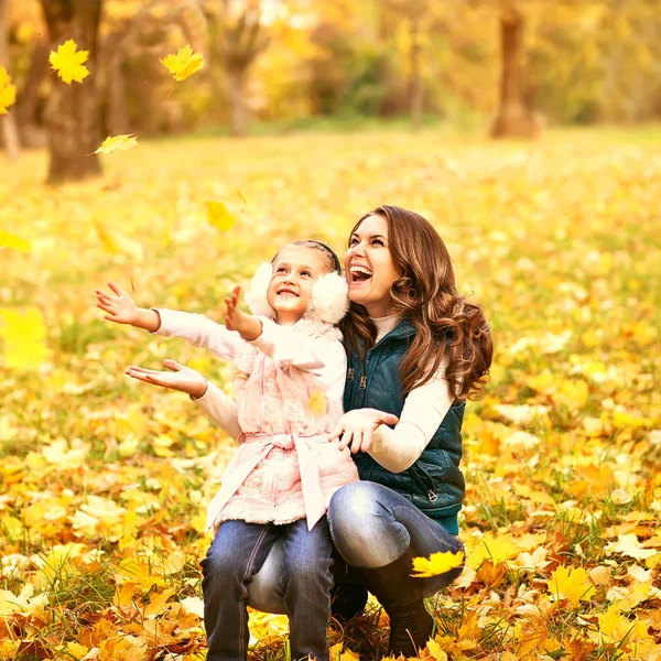Mother and daughter having fun in the autumn park among the fall — Stock Photo, Image