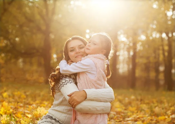 Mother and daughter having fun in the autumn park among the fall — Stock Photo, Image