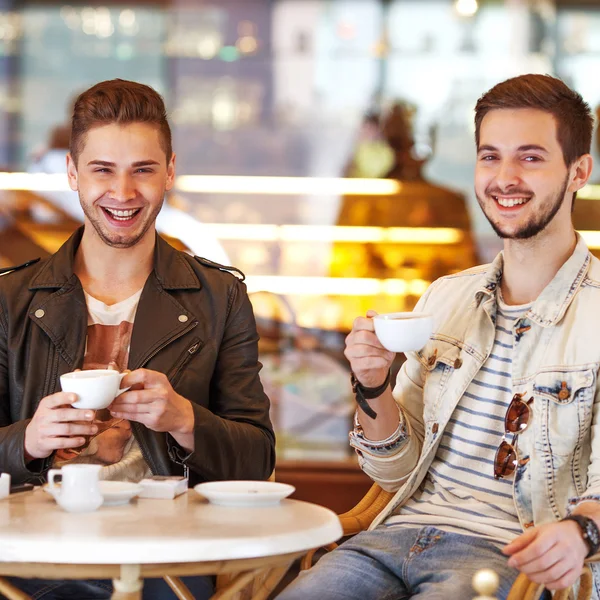 Two young hipster guy sitting in a cafe chatting and drinking co — Stock Photo, Image