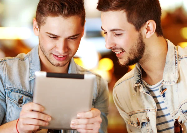 Two young men students using tablet computer in cafe — Stock Photo, Image