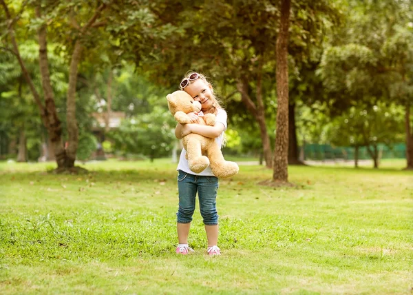 Petite fille avec ours en peluche dans le parc heureux — Photo