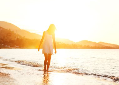 Gün batımında sahilde yürüyen güzel kız, özgürlük kavramı.